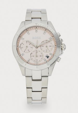 Montre en métal argenté avec un cadran rose, trois sous-cadrans, des accents en cristal et une fonction date. Équipée d'un bracelet en acier inoxydable et d'une lunette texturée.