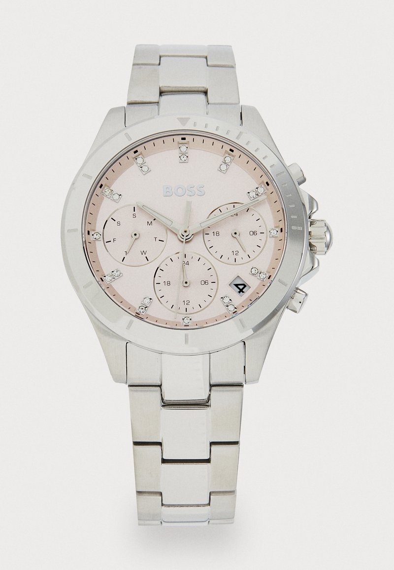 Ασημένιο μεταλλικό ρολόι με ροζ καντράν, τρία υποκαντράν, κρυστάλλινες λεπτομέρειες και λειτουργία ημερομηνίας. Περιλαμβάνει βραχιόλι από ανοξείδωτο ατσάλι και υφή στην στεφάνη.