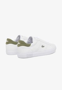 Sneakers in pelle bianca con dettagli traforati, inserti in suede verde sul tallone e suola in gomma bianca. Presentano il logo del marchio sul lato.