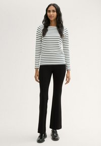 Long-sleeve striped top in white and navy blue paired with black flared pants and black shoes. The fabric appears smooth and fitted.