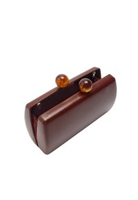 Brązowa skórzana kopertówka o zaokrąglonym kształcie, z dwoma mosiężnymi zapięciami w kolorze bursztynu i miękkim materiałowym wnętrzem.