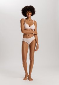 Bra rosa chiaro e slip coordinato, realizzati in tessuto morbido, con rifiniture in pizzo sul reggiseno e bordi senza cuciture sulla biancheria intima.