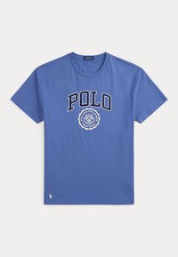 Μπλε μπλουζάκι Polo Ralph Lauren με το κείμενο "POLO" και στρογγυλό έμβλημα με την επιγραφή "Polo Ralph Lauren New York" στο κέντρο μπροστά.