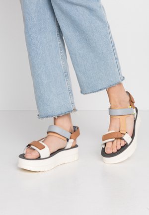 Chunky platform sandals with a white base, grey and tan straps, and a textured black insole; adjustable buckle closures.