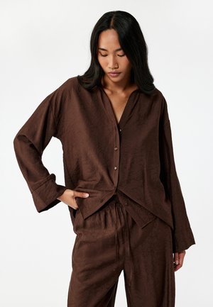 Conjunto de salón texturizado en marrón que incluye una camisa de botones de corte relajado y pantalones a juego con cintura elástica, ambos con un patrón sutil.