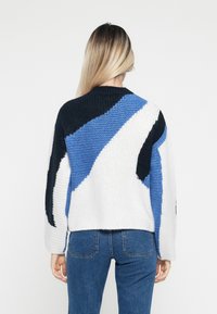Strikkegenser med teksturert design som har abstrakte blå, svarte og hvite deler. Avslappet passform med lange ermer og rund hals.
