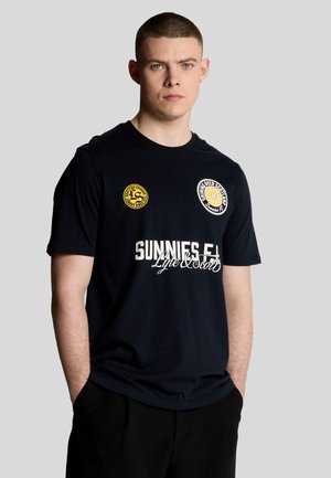Marineblå kortærmet t-shirt med hvid tekst med "SUNNIES F.C." og to runde mærker i gul og hvid på brystområdet.