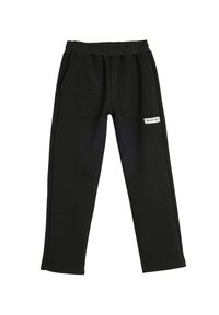 Pantalones de chándal negros con cinturilla elástica, dos bolsillos frontales y una etiqueta con "ENJOY 90's" en un lado. Textura de tela suave.