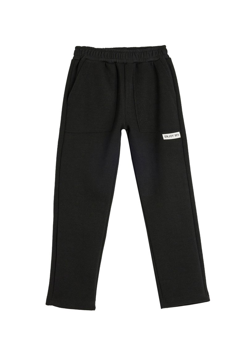 Pantalones de chándal negros con cinturilla elástica, dos bolsillos frontales y una etiqueta con "ENJOY 90's" en un lado. Textura de tela suave.