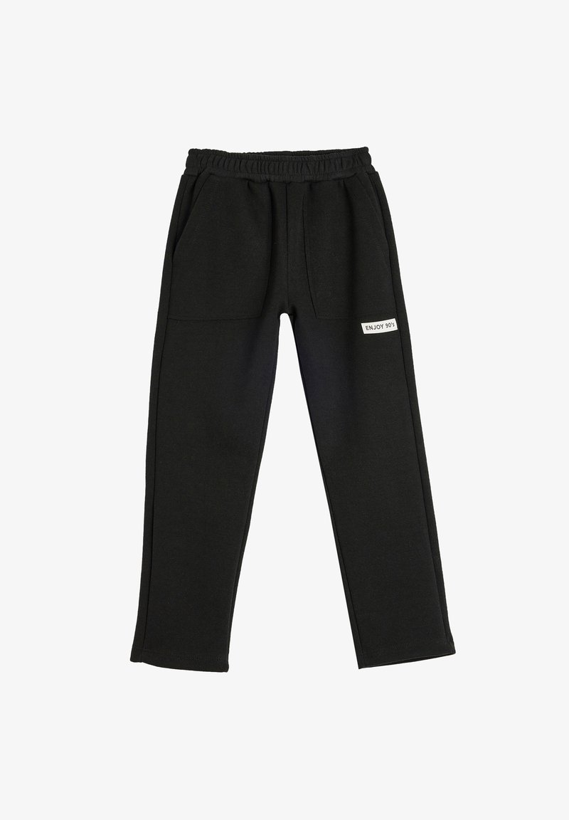 Black sweatpants featuring an elastic waistband, two front pockets, and a label with "ENJOY 90's" on the side. Smooth fabric texture.