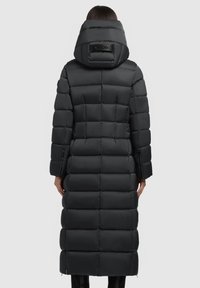 Sort pufferjakke med lang design, horisontal quiltet mønster, stor hætte og et logo-tags på ryggen. Glat, skinnende stof.