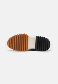 Rubber sneaker sole with ribbed texture; features orange, cream, and black sections. Prominent branding on the cream area.