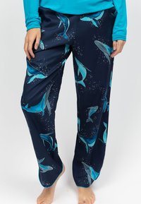 Marine blauwe pyjamabroek met een walvispatroon in turquoise, voorzien van een zachte textuur en een losse pasvorm. Het ontwerp bevat kleine accentdetails die op luchtbelletjes lijken.