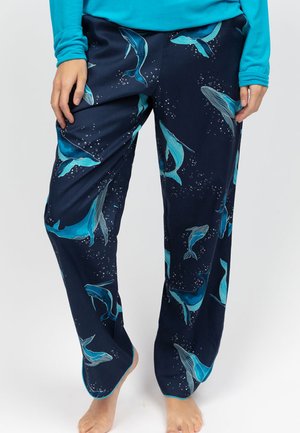 Pantaloni da pigiama blu navy con motivo balena in turchese, caratterizzati da una texture morbida e una vestibilità ampia. Il design include piccoli dettagli accentuati che ricordano bolle.