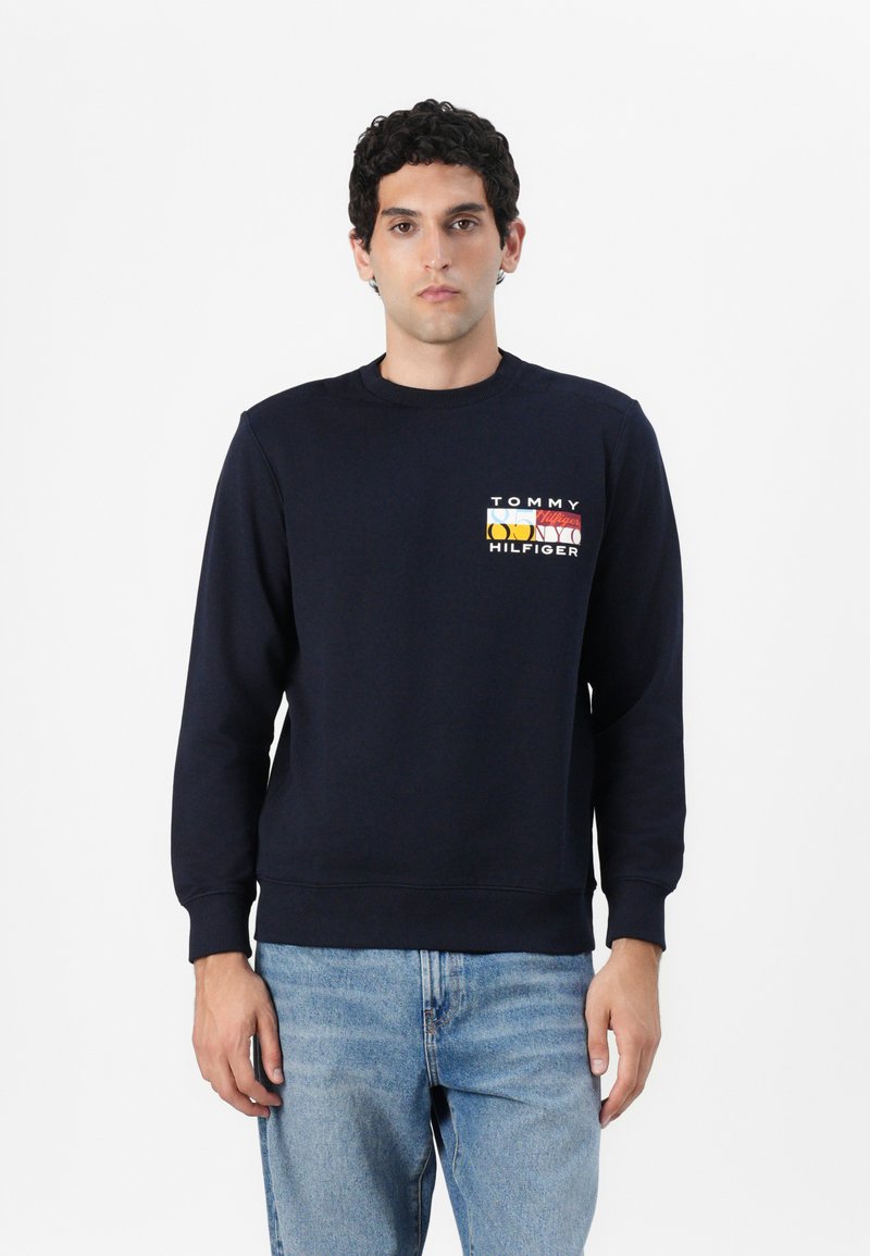 Marineblå bomullssweatshirt med ribbestrikkede mansjetter og krage. Har en flerfarget "Tommy Hilfiger"-logo på brystet. Klassisk passform.