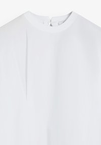 Weißes Blusenshirt mit rundem Ausschnitt, verfügt über eine Knopfverschlüsse im Rücken, glatte Textur und eine subtile Falte in der Mitte.