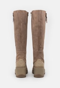 Brown suede knee-high boots with a chunky tan heel, back zipper, and reinforced heel accents. Smooth texture and clean stitching details.