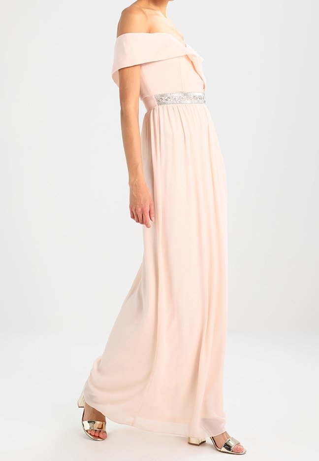 Robe maxi rose pâle à épaules dénudées avec un corsage ajusté, une taille empire et des accents de sequins argentés. Tissu doux, fluide et texture lisse.
