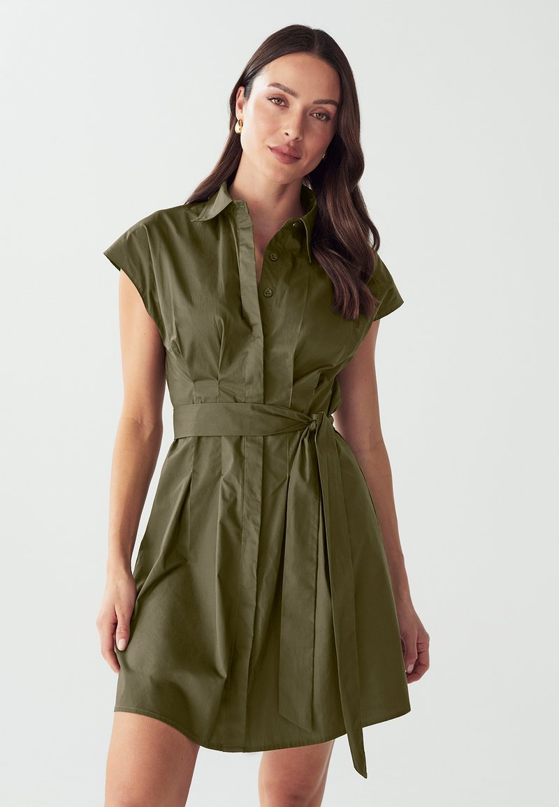 Abito camicia verde oliva con colletto, maniche corte e chiusura a bottoni, con vita legata e design a gonna plissettata. Texture liscia.