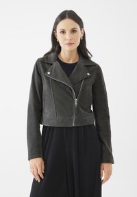 Chaqueta de motocicleta de ante gris oscuro, recortada, con cremallera plateada, cuello de solapa y dos bolsillos frontales. Llevada sobre una blusa negra.