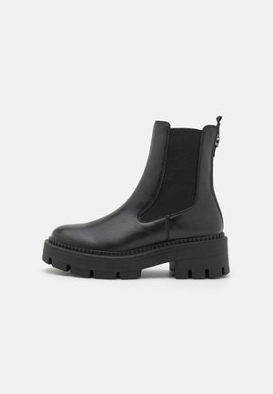 Czarne skórzane botki do kostki z elastycznymi panelami bocznymi, masywną gumową podeszwą oraz fakturowanym wierzchem, wyposażone w pętlę z tyłu dla łatwego zakładania.