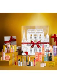 Un calendrier de l'avent beauté présente un fond doré, un emballage décoratif avec un design parisien, et une variété de produits de soin de la peau et de maquillage.