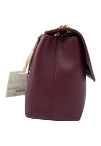 Borsa a mano in pelle borgogna con finitura testurizzata, dotata di tracolla a catena, chiusura con flap superiore e un'etichetta del prezzo visibile sul lato.