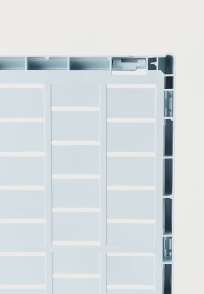 Ελαφρώς γαλάζιο πλαστικό κουτί με κατώτατο μέρος που εμφανίζει μοτίβο πλέγματος και ενισχυμένες άκρες, σε κοντινή λήψη από πάνω σε λευκό φόντο.