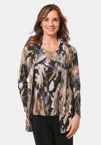 Langdurige top met een meerkleurig abstract patroon in beige, zwart en blauw. Heeft een ronde hals en een losse, vloeiende pasvorm.