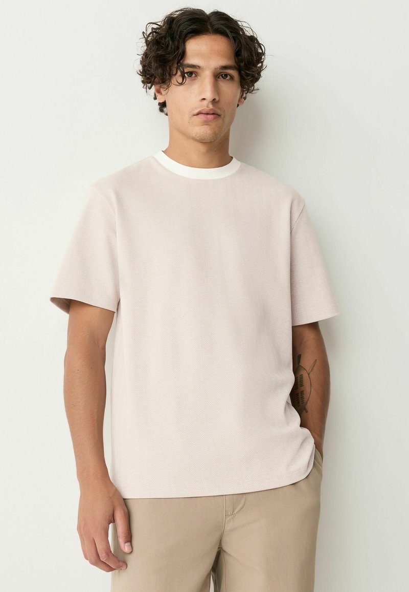 Helles rosa T-Shirt mit kurzen Ärmeln und einem strukturierten Fischgrätmuster sowie weißem Rundhalsausschnitt. Es hat einen lässigen Schnitt und einen geraden Saum.