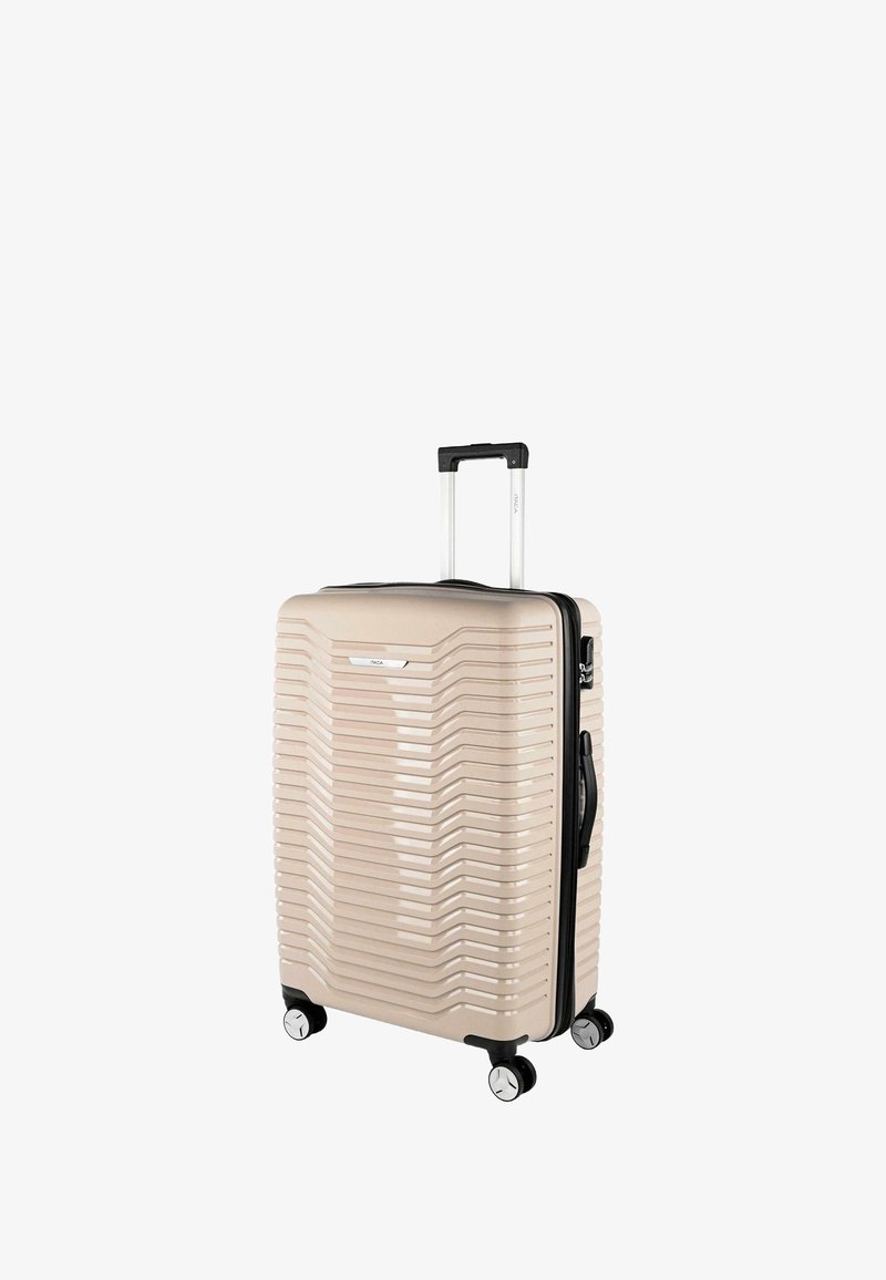 Maleta rígida de tamaño mediano en color beige con diseño acanalado, asa retráctil, cuatro ruedas y cremallera negra. Cuenta con un asa lateral.