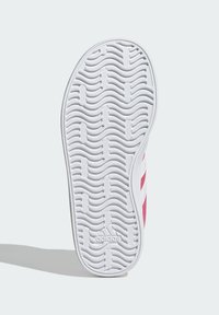 Suela de calzado Adidas con un patrón de banda ondulada, predominantemente blanca con acentos en rosa. Presenta el logotipo de Adidas cerca del talón.