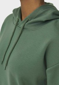 Grüne Kapuzenjacke aus Baumwollstoff, mit Kordelzugkapuze und geripptem Kragen. Glatte Textur mit doppelt genähten Nähten für Langlebigkeit.