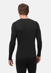 Sort langærmet thermotrøje med et tætsiddende design, ribbet tekstur og rund halsudskæring. Søm detajler på skuldrene, glat kant.