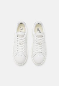 Witte sneakers met een glad leren bovenwerk, ronde neus, platte witte veters en een minimalistisch ontwerp. Het interieur heeft lichtgrijze accenten.