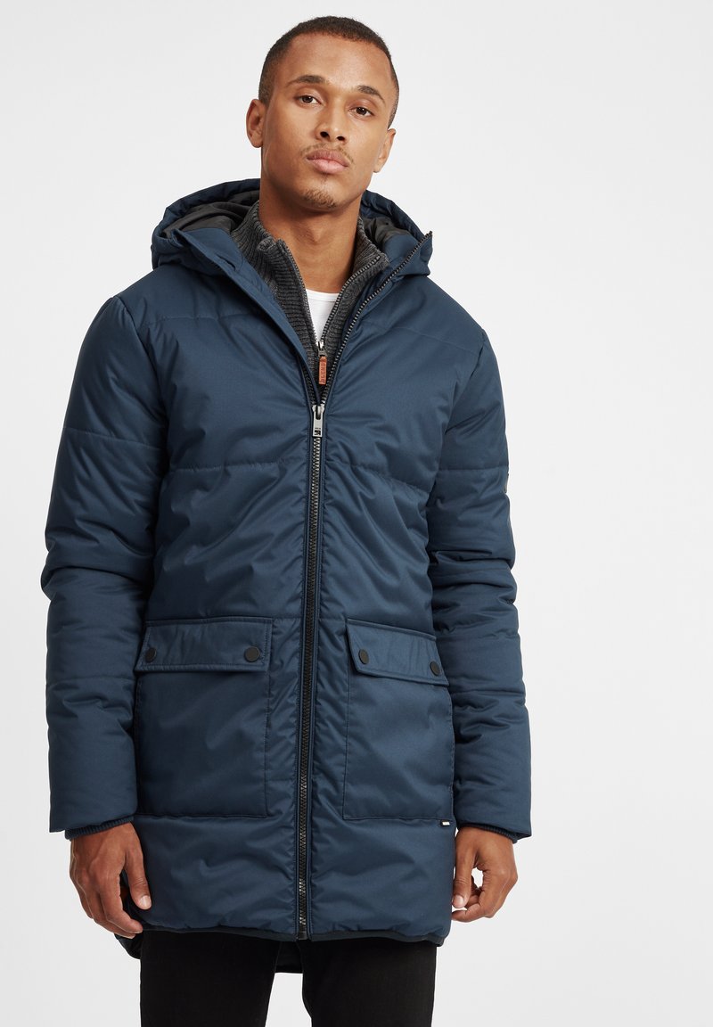 Parka albastră închis, izolată, cu glugă, fermoar frontal, două buzunare laterale și un căptușeală texturată. Dispune de un design casual.