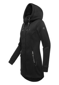 Fekete kapucnis dzseki texturált anyagból, hosszú ujjal, cipzáras zsebekkel, állítható húzózsinórral és ívelt hátvonalal.