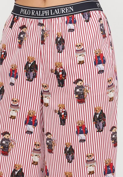Red striped pajama bottoms featuring cartoon bears in various outfits. Fabric is soft, with a logo waistband and multiple bear illustrations.
