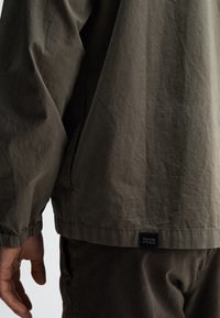Khaki korte jas met elastische manchetten, gestructureerde stof, zijzakken en een label met de tekst "butcher of blue" aan de zoom.