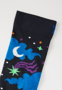 Chaussettes noires ornées d'un motif de nuages bleus, de lune croissante blanche, de comètes violettes et d'étoiles colorées. Poignet côtelé en haut.