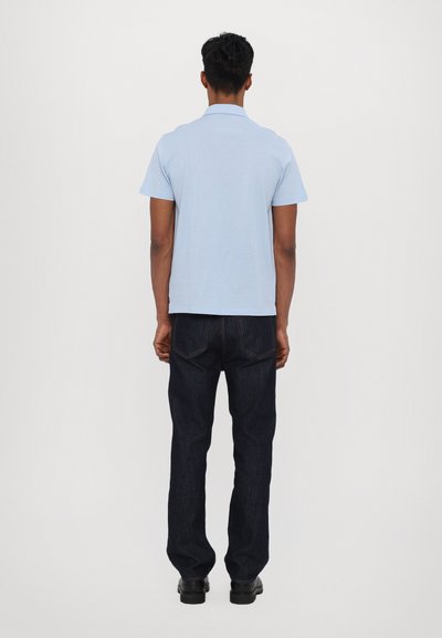 Ανοιχτό μπλε κοντομάνικο πουκάμισο πόλο, συνδυασμένο με σκούρες τζιν παντελόνες, που διαθέτει κλασική γραμμή και καθαρό φινίρισμα. Απλός σχεδιασμός χωρίς ορατά σχέδια.