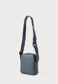 Sötétkék szintetikus keresztpántos táska négyzet alakú, texturált felülettel, állítható pánttal és cipzáras záródással. Minimalista kialakítás.