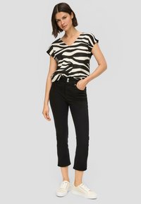 Zwart-wit gestreepte short-sleeve top met een V-hals, gecombineerd met hoge zwarte jeans en witte sneakers.