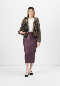 Leopard-print fleece zip-up jacket, white fitted top, knee-length burgundy leather skirt, and black pointed-toe flats, complemented by a black bag.