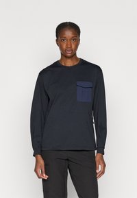 Tricou cu mânecă lungă, de culoare bleumarin, confec�ționat din bumbac, având un buzunar texturat pe piept și un guler rotund clasic. Material din amestec de poliester și bumbac.