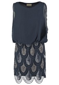 Robe marine avec un haut léger et une jupe texturée en perles présentant des écailles superposées. Manches transparentes et décolleté rond.