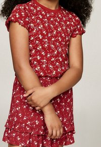Rotes Kleid mit Blumenmuster, kurzen, gerafften Ärmeln und einem schichtweisen Rock. Hergestellt aus strukturiertem Stoff; verfügt über bunte Blumenakzente.