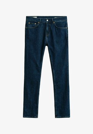 Donkerblauwe spijkerbroek met vijfzakkenontwerp, knoop- en ritssluiting, en een recht model, plat liggend op een witte achtergrond weergegeven.