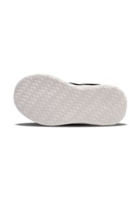 Weiße Gummisohle mit strukturiertem Profil, abgerundeten Kanten und glatter Oberfläche. Schwarzes Obermaterial mit subtilen Branding-Details.