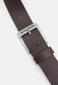 Cinturón de cuero marrón con una hebilla de metal plateado, con el nombre de la marca "JACK & JONES" grabado y cinco agujeros ajustables.